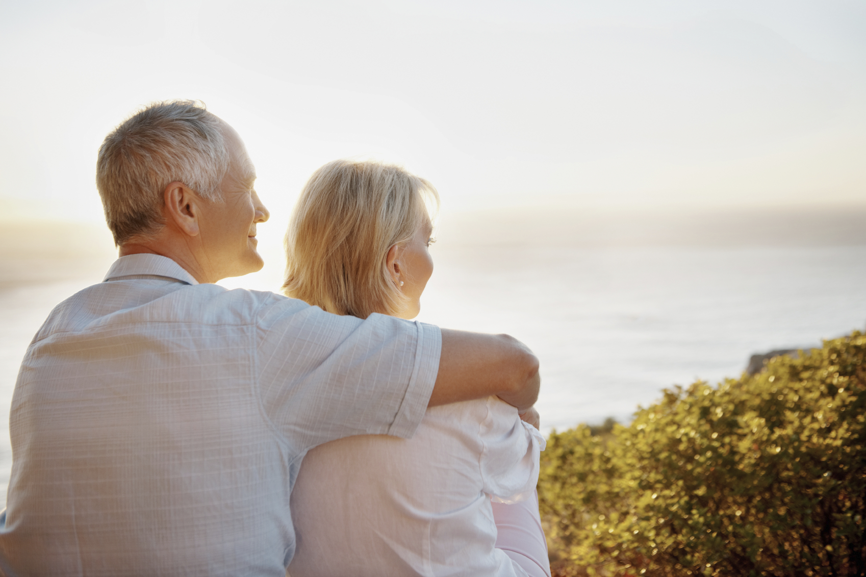 Rear-view of a blissful senior couple embracing against a picturesque sunset together